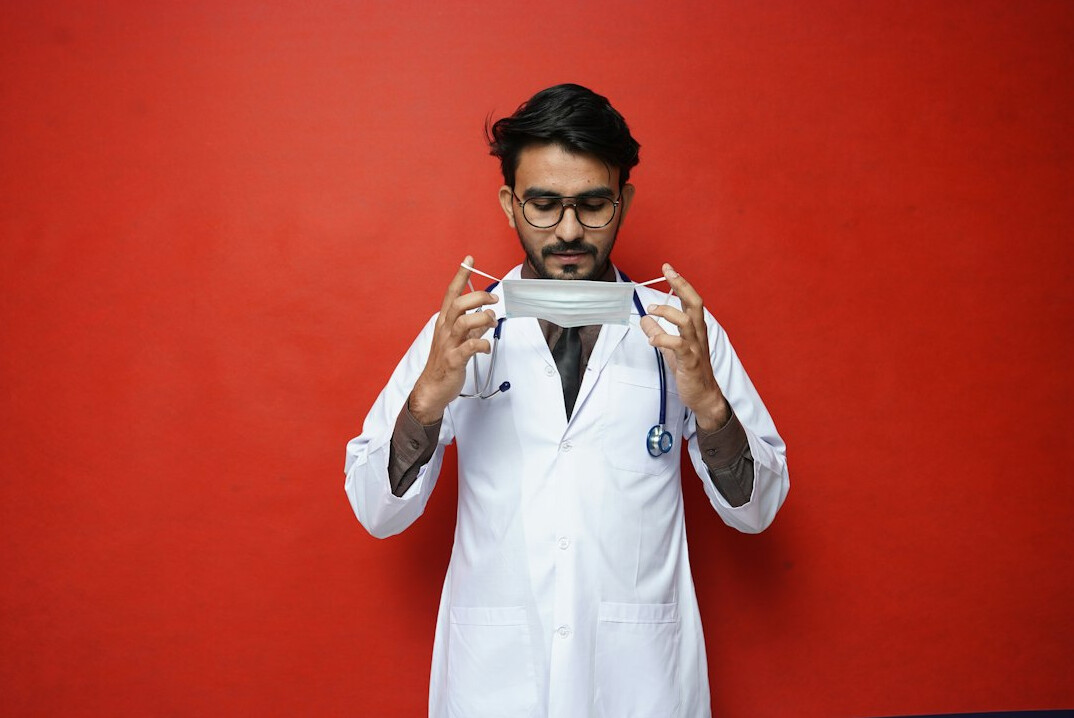 Smiling male doctor with glasses and beard in white coat